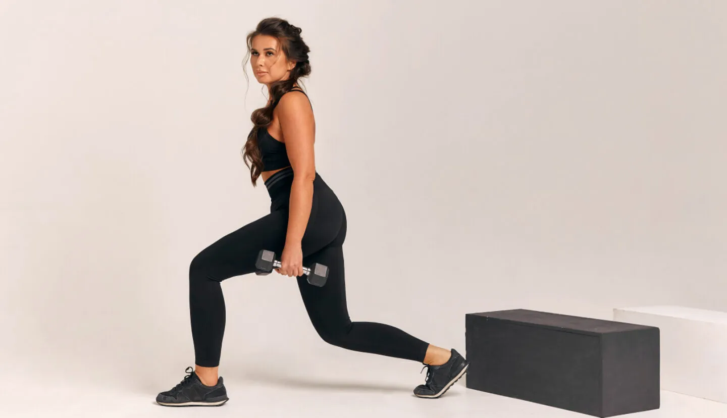 Kobieta wykonująca wykroki z hantlami podczas treningu siłowego na siłowni FitLife Zamość